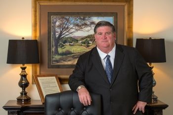 Jonathan E. Edwards, Esq. posing for photo in office next to office chair 